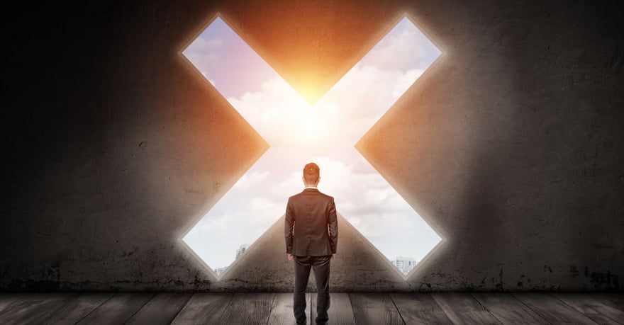 Business professional standing in a dark room facing a large X-shaped opening filled with sunlight and sky, symbolizing a critical business decision, risk assessment, or strategic turning point.