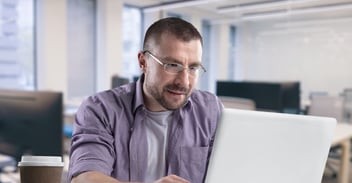 Business professional reviewing information on a laptop in a modern office workspace.”