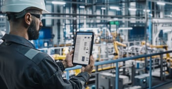 Factory engineer using tablet to monitor production during Cloud ERP migration in a modern manufacturing plant