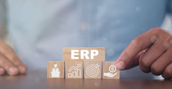 ERP Due Diligence concept: hand arranging ERP blocks with finance, growth, and target icons on a desk.