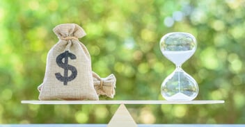 ERP Implementation Cost Over Time represented by a money bag and hourglass balanced on a scale.