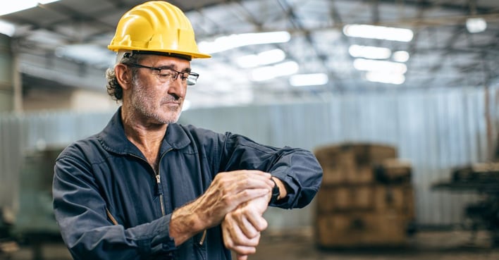 Factory worker checking time inside a manufacturing facility during operational delays and production downtime.