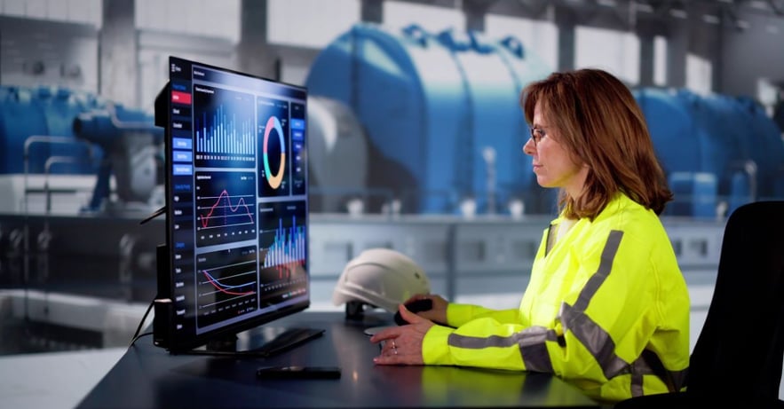 Engineer reviewing manufacturing analytics dashboard on computer, monitoring production performance and operational metrics