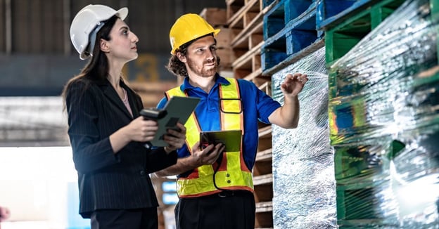 Warehouse team inspecting inventory and pallet stock with tablets to verify data accuracy and inventory integrity.