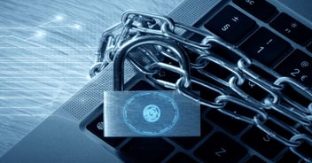 Laptop keyboard wrapped in metal chains with a digital padlock and fingerprint icon, representing cybersecurity threats, data protection, and security risks targeting ERP systems and supply chain operations.