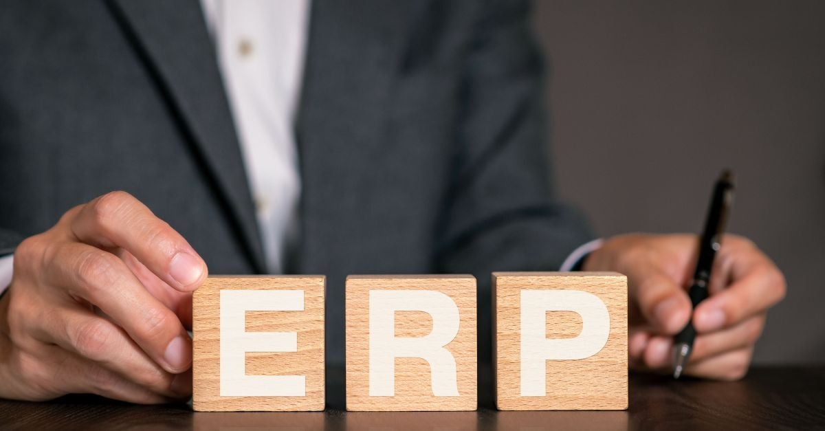 Hands arranging wooden ERP blocks on desk, symbolizing Cloud ERP readiness assessment and business planning strategy