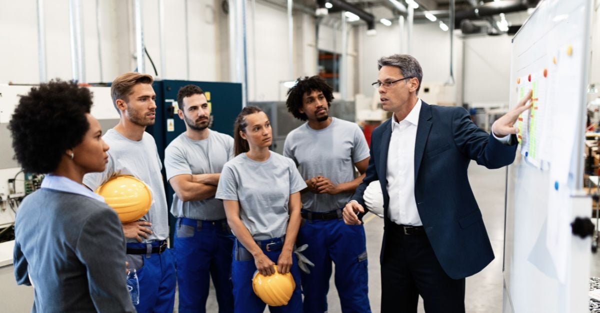 Manufacturing team reviewing production metrics and workflows during an ERP readiness planning meeting on factory floor.
