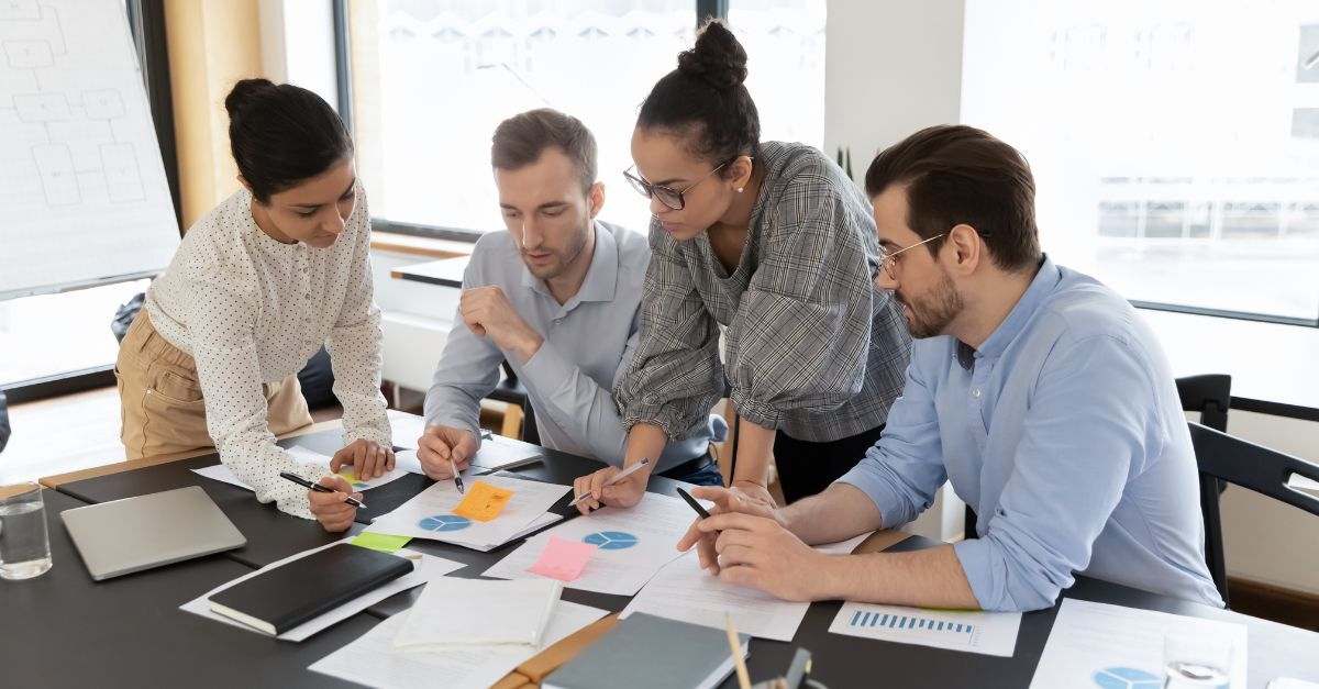 Team collaborating over charts and documents in office meeting, aligning strategy for ERP success and data-driven decisions
